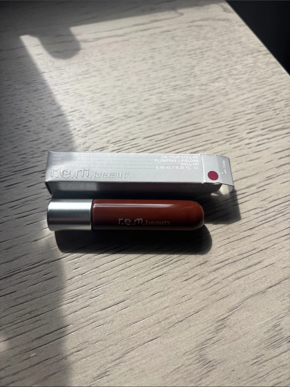 REM Beauty On Your Collar Plumping Lip Gloss — Deep Brown Roll Up